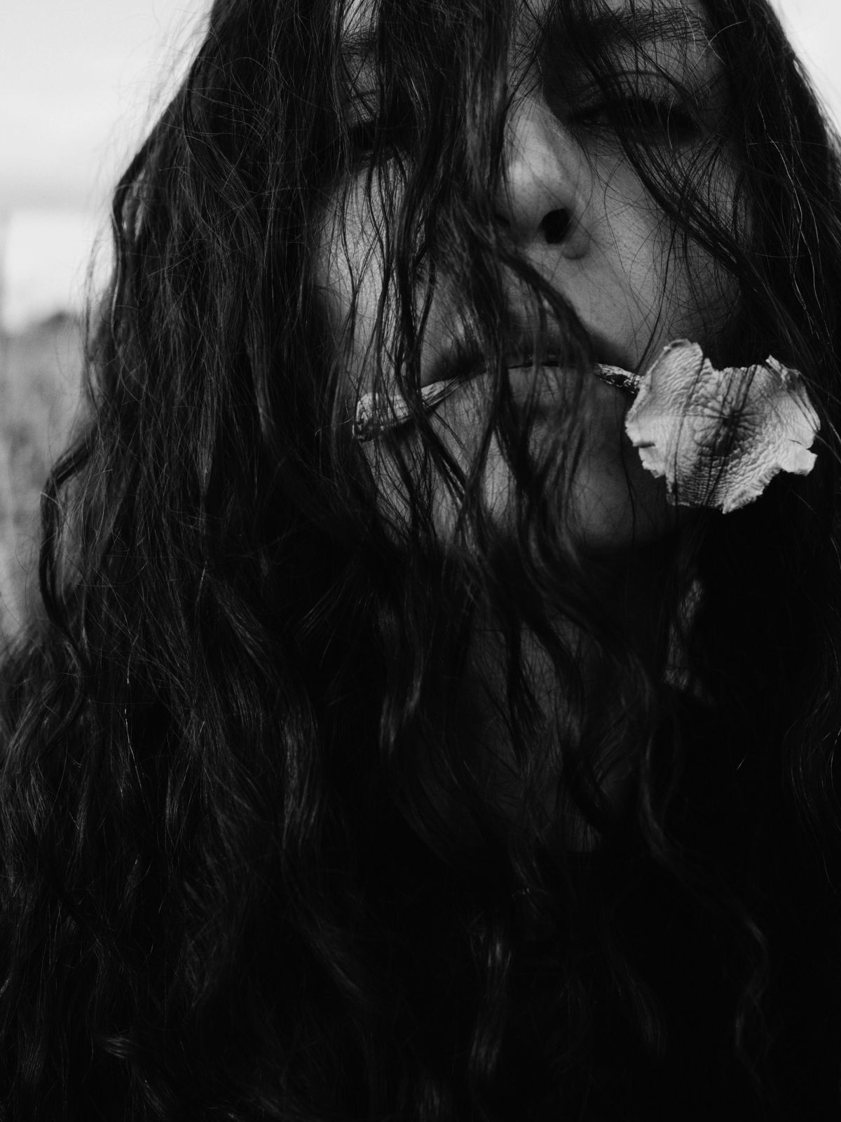 Women in black and white with hair in her face eating a mushroom