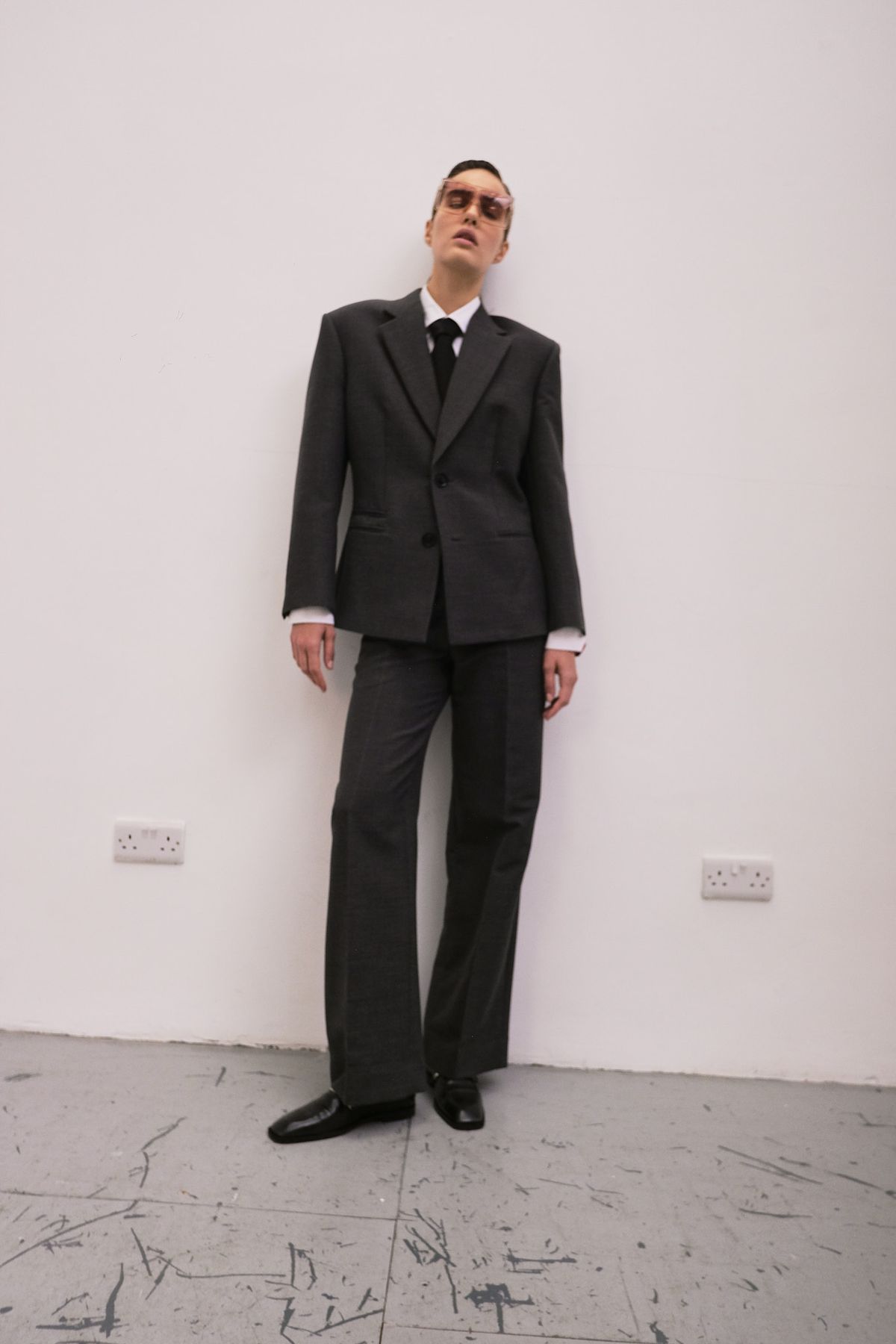 Model wearing a suit and tie in a white studio with grey distressed floor