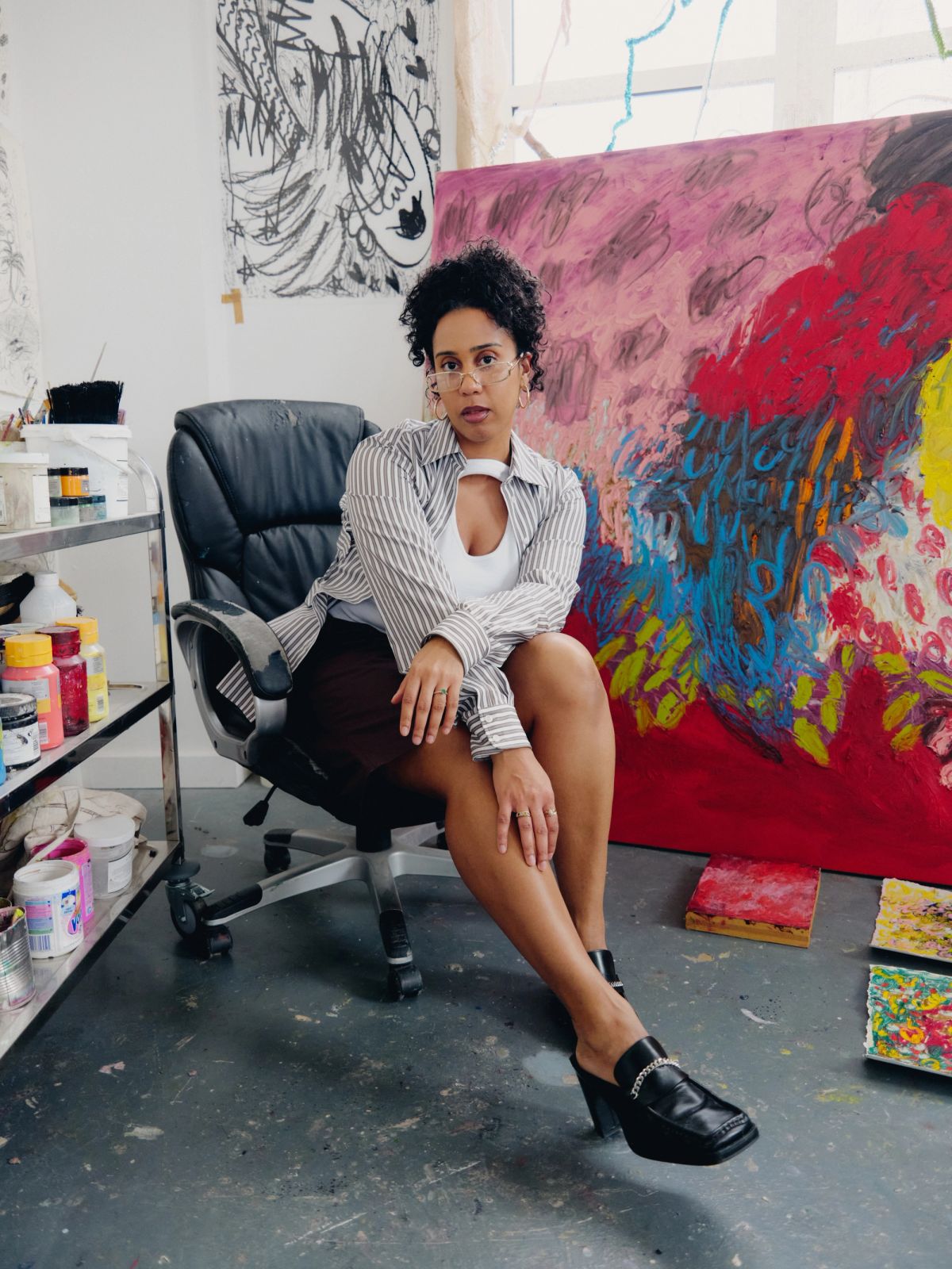 artist in her studio sitting in black leather office chair  
