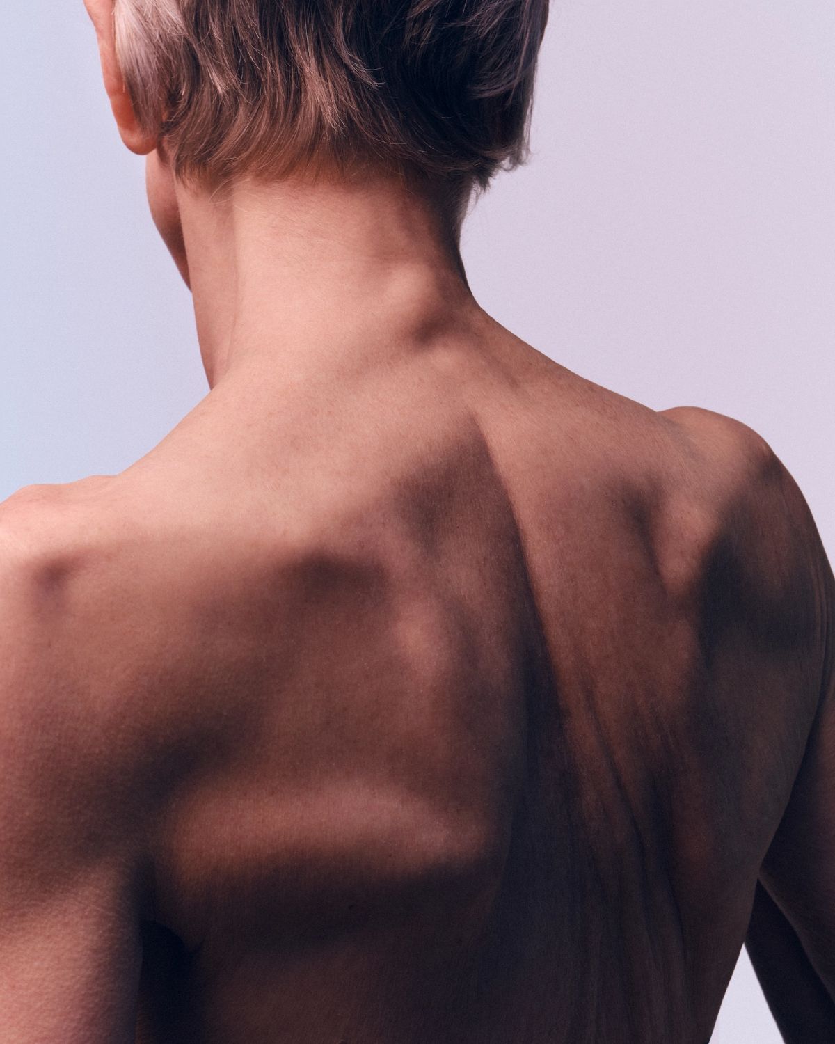 back crop of a womens head, neck and upper back in a studio