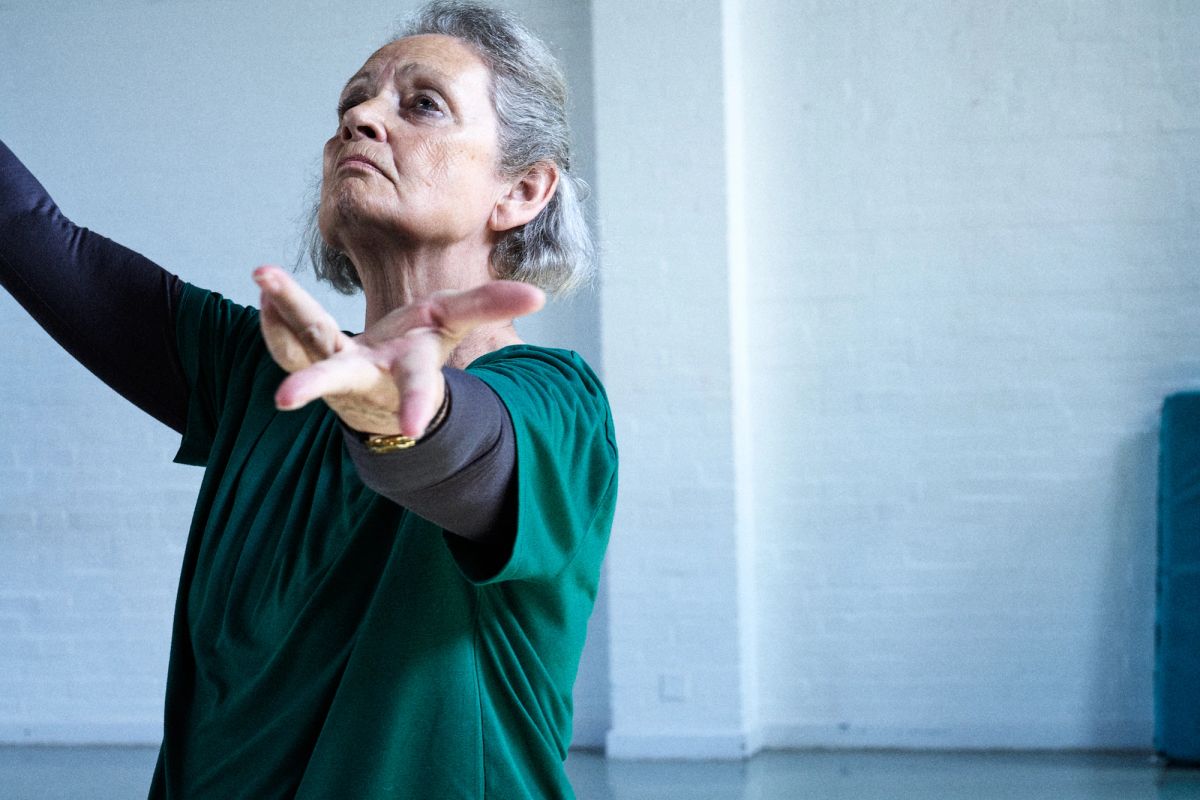 women holding up her arms wearing a green top in a dance studio