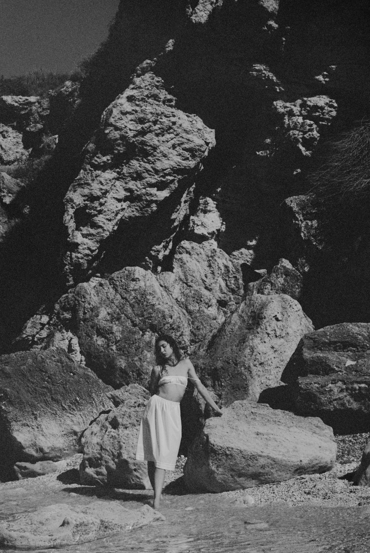 Woman standing by rocks in skirt and bra