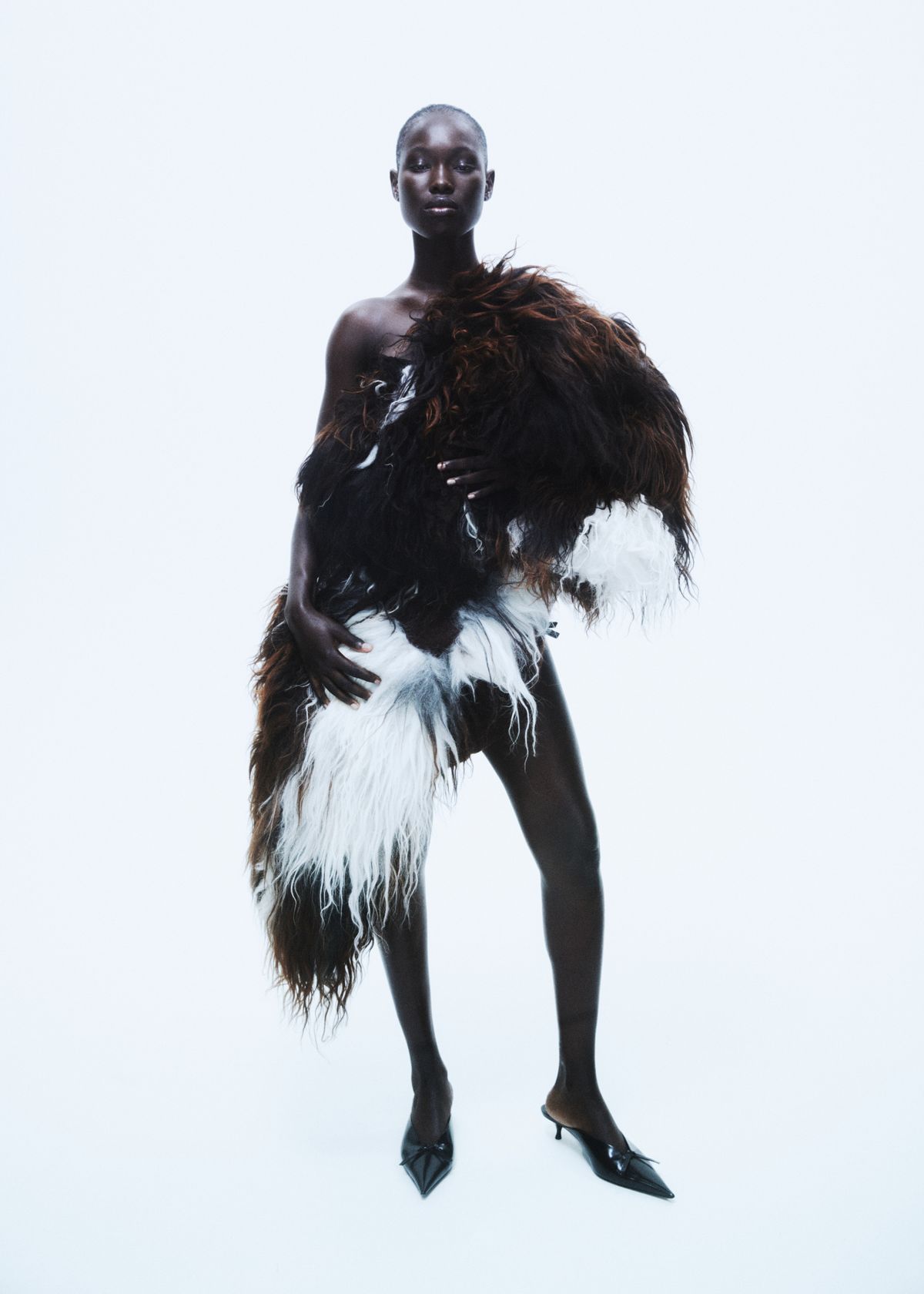 model standing on white background draping a coat over her body