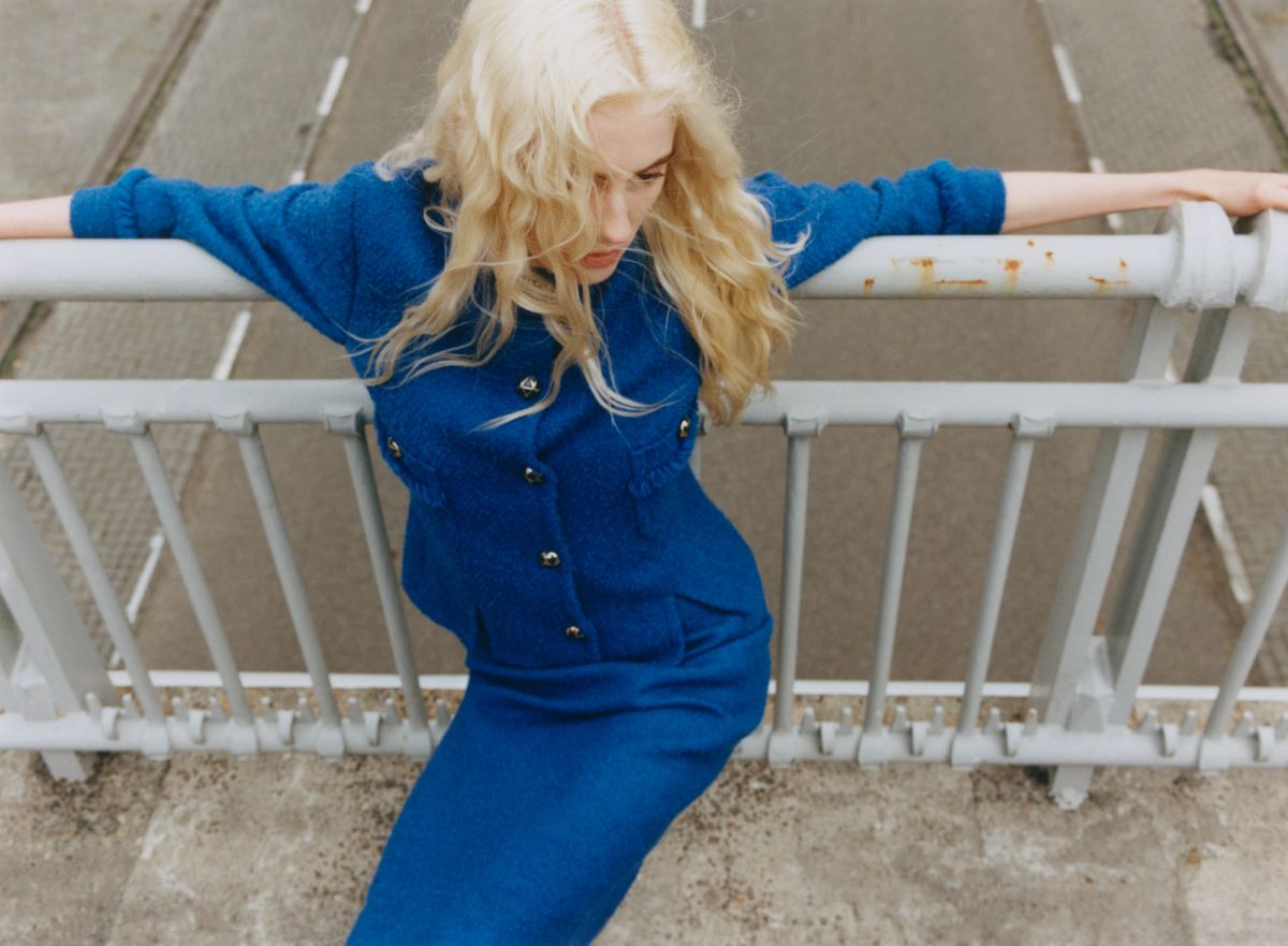 women leaning on railings next to a road wearing blue