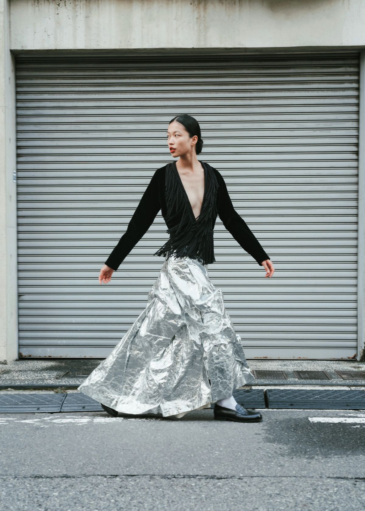 a model walking in a grey urban street wearing a sliver skirt