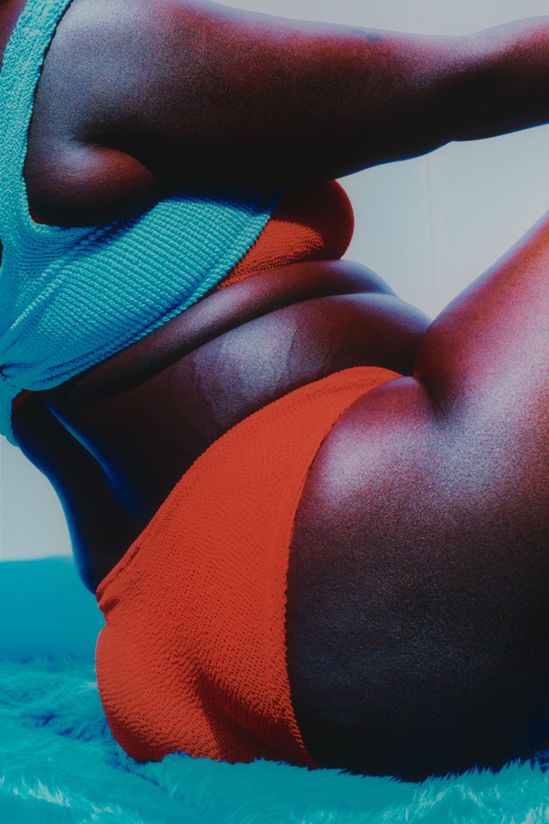 cropped shot of model wearing red bikini on sitting on fluffy ground