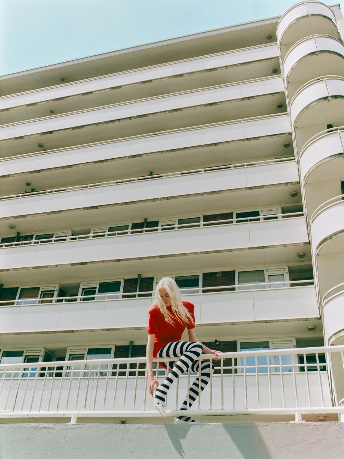women adjusting her shoes sitting on white railings