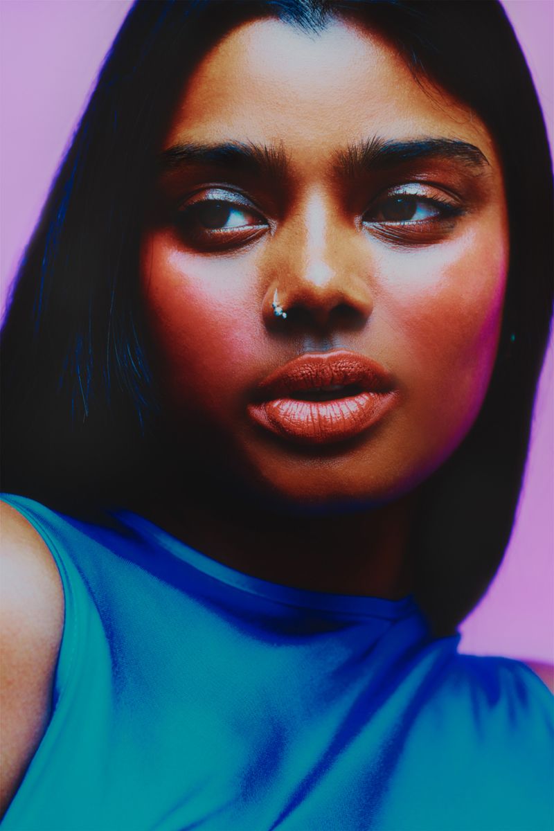 close up of model on purple background wearing a blue dress