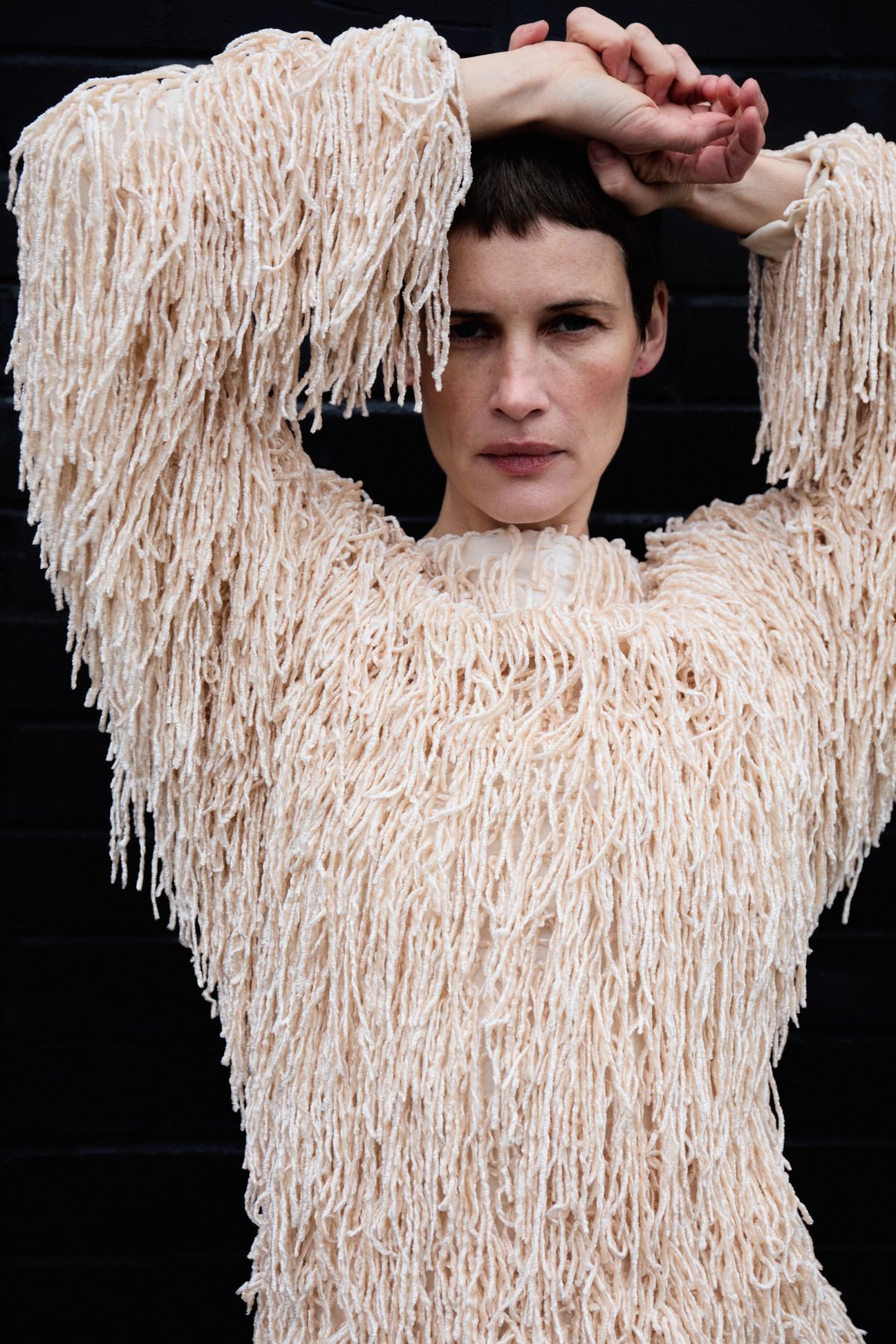 Model wearing textured dress with arms above head