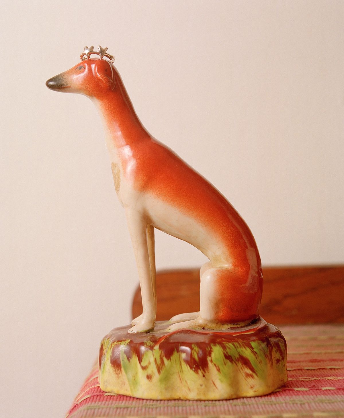 A porcaline figurine of a dog with a ring resting on its head