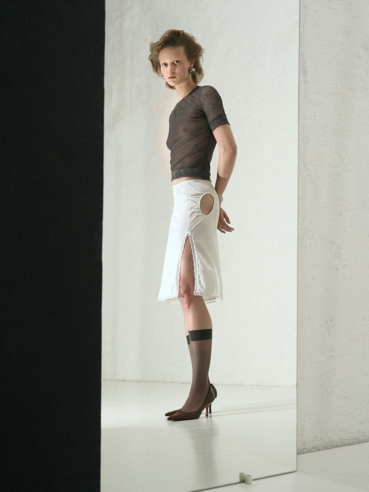 model in white skirt and black top in a studio