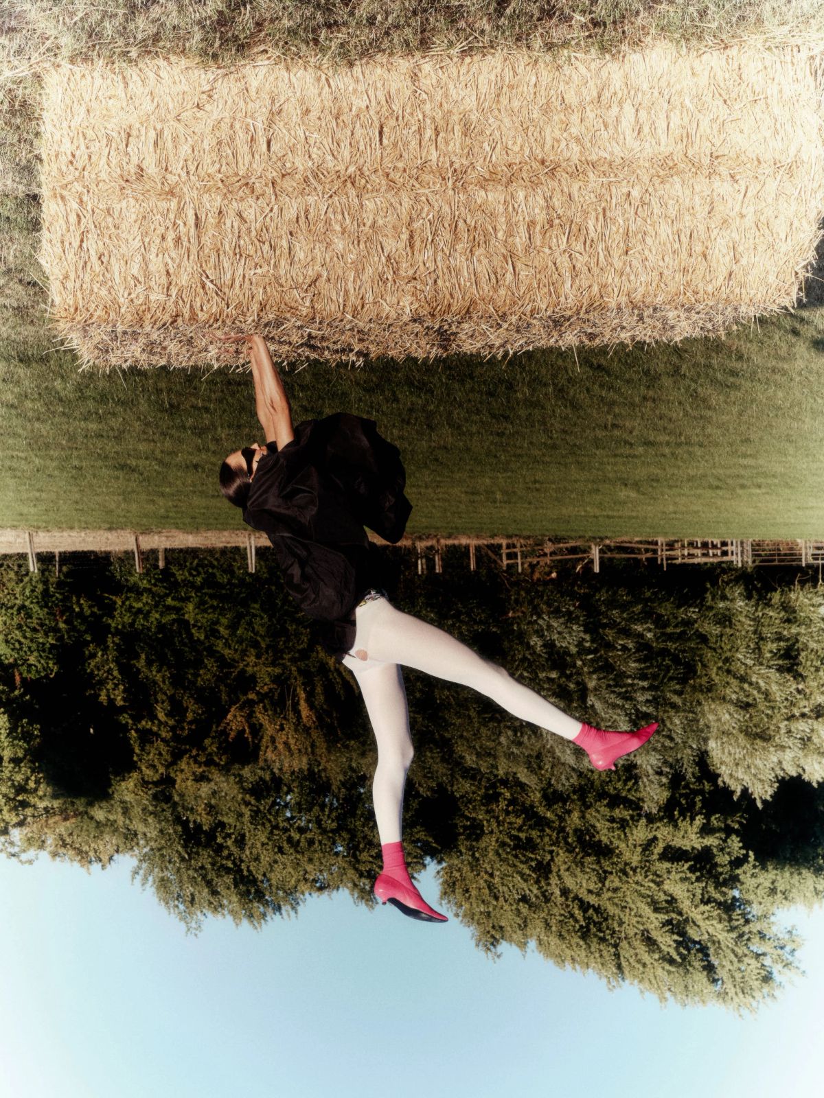 Model doing a handstand on a hay bale with pink socks and shoes