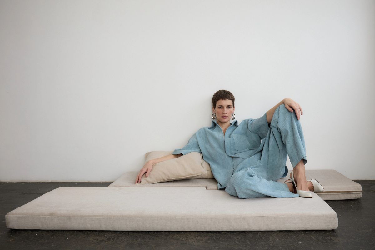 Model wearing pale blue suede coord sitting on cushions