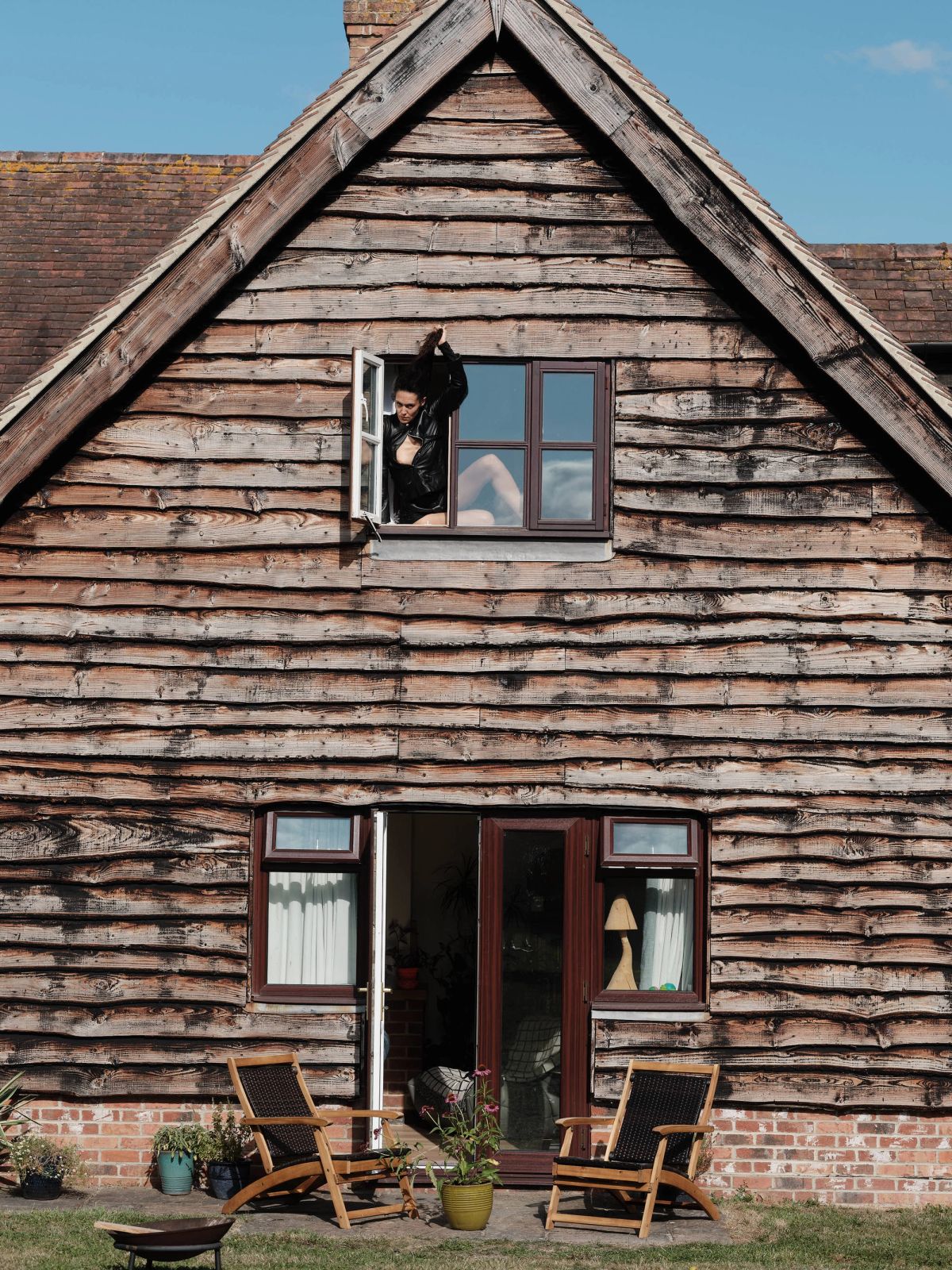 a wooden barn with a model in black hanging out of the top window