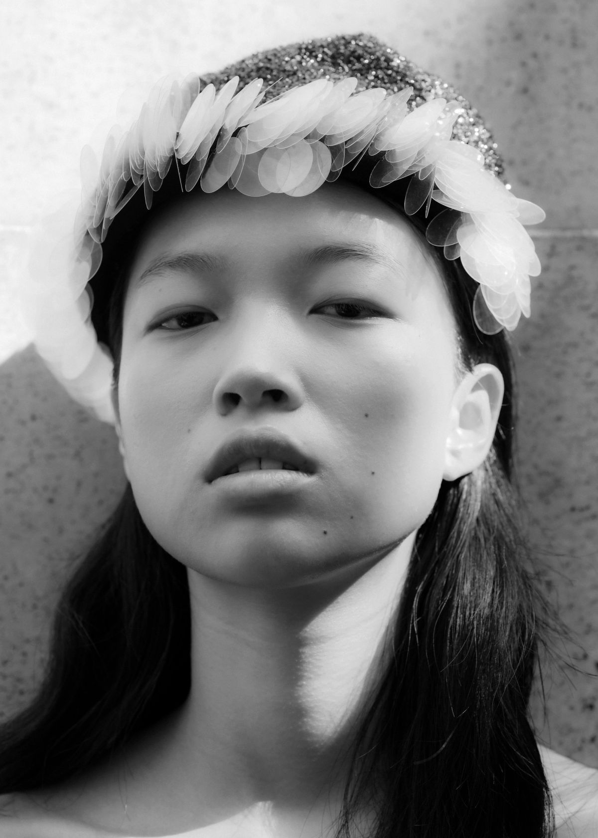 close up shot of a model with a sequin headress staring directly to camera standing outside
