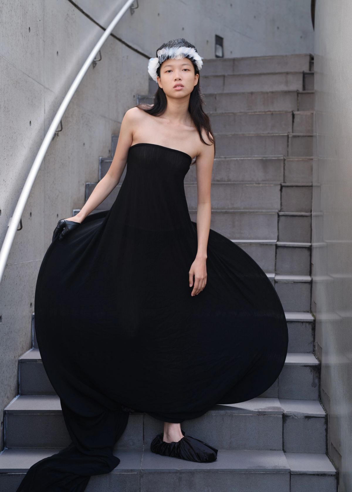 model wearing a black volumnous dress standing on a concrete stairwell