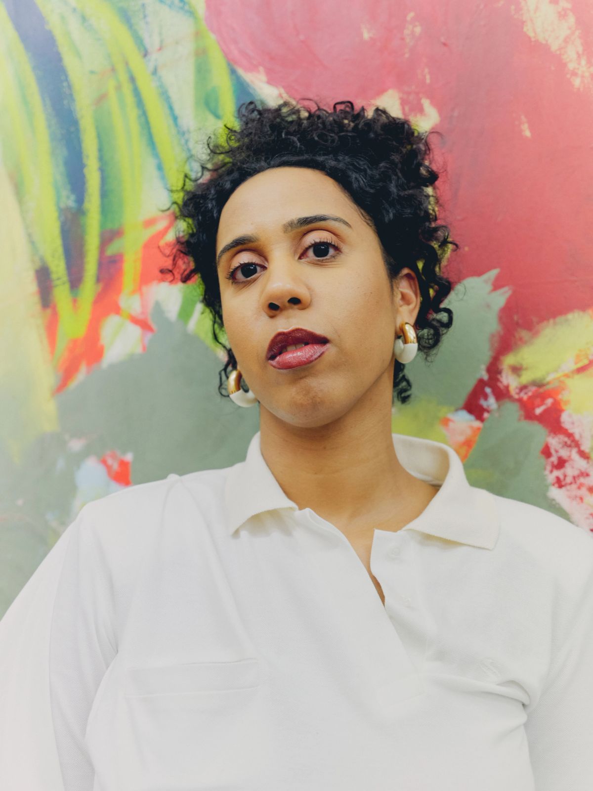 Close up of Artist in front of her paintings wearing a white dress