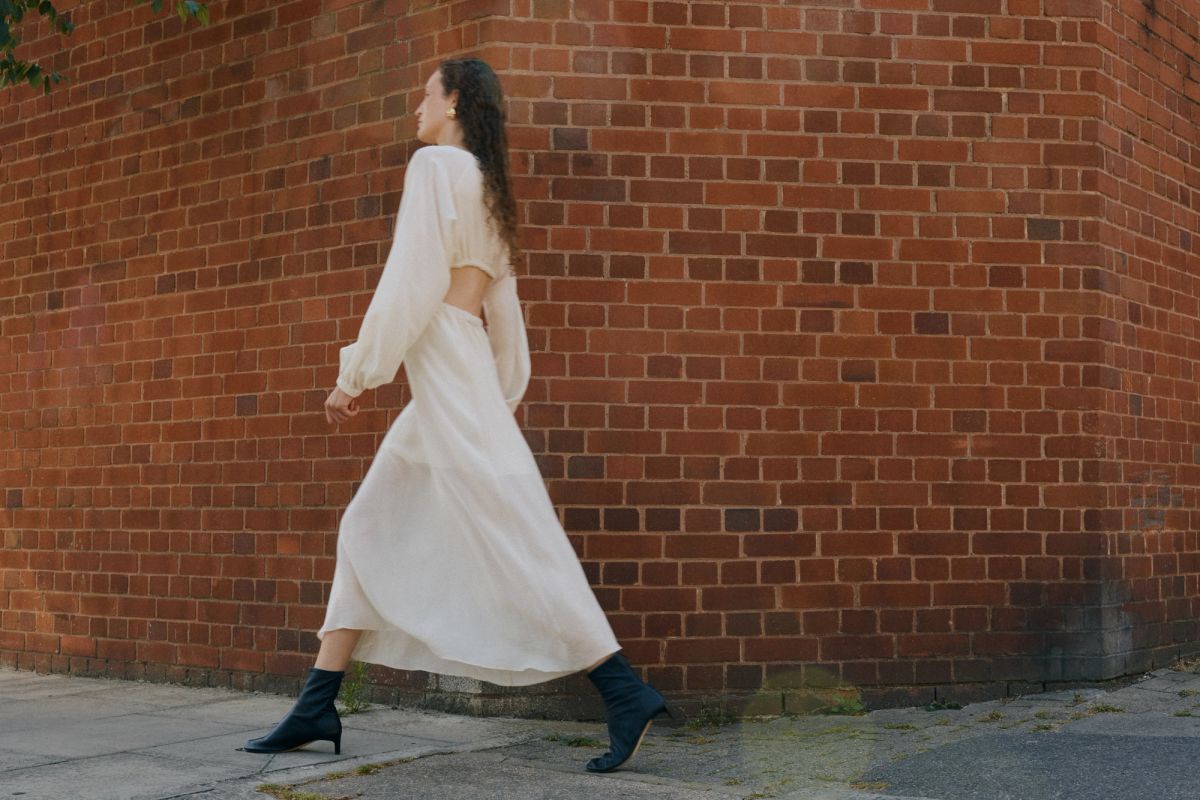 Woman walking by red brick wall