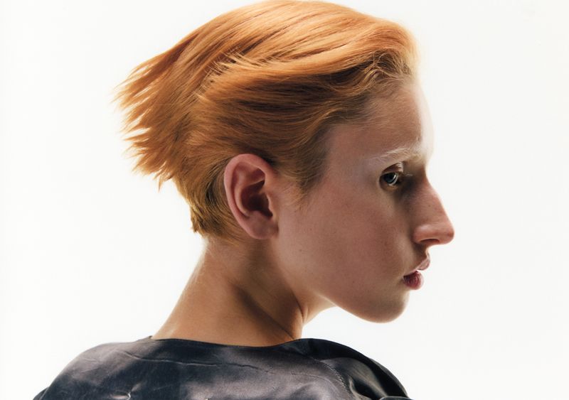 model with red hair in profile on a white background