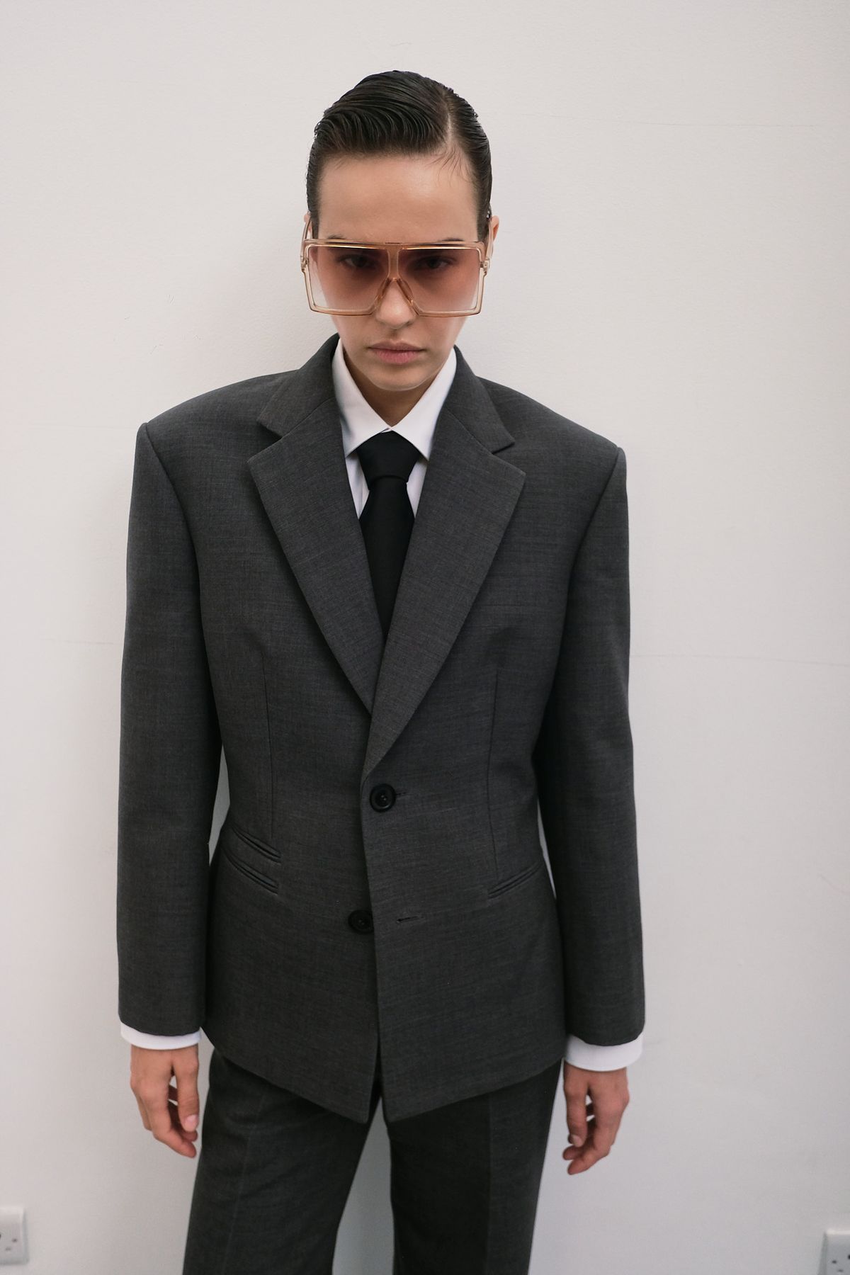 model standing in a studio with a suit snd sunglasses