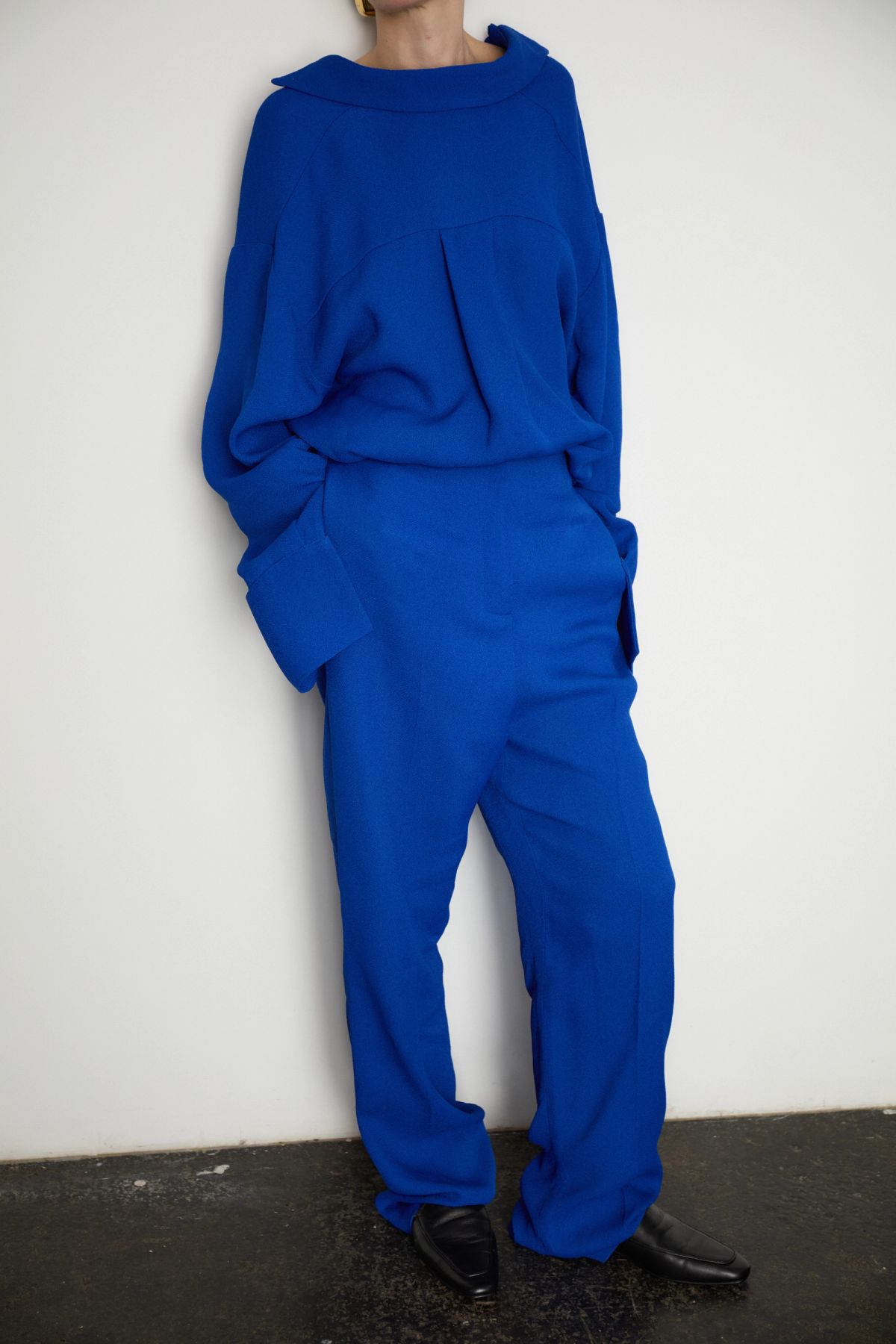 Model leaning against white wall wearing Yves Klein blue coord
