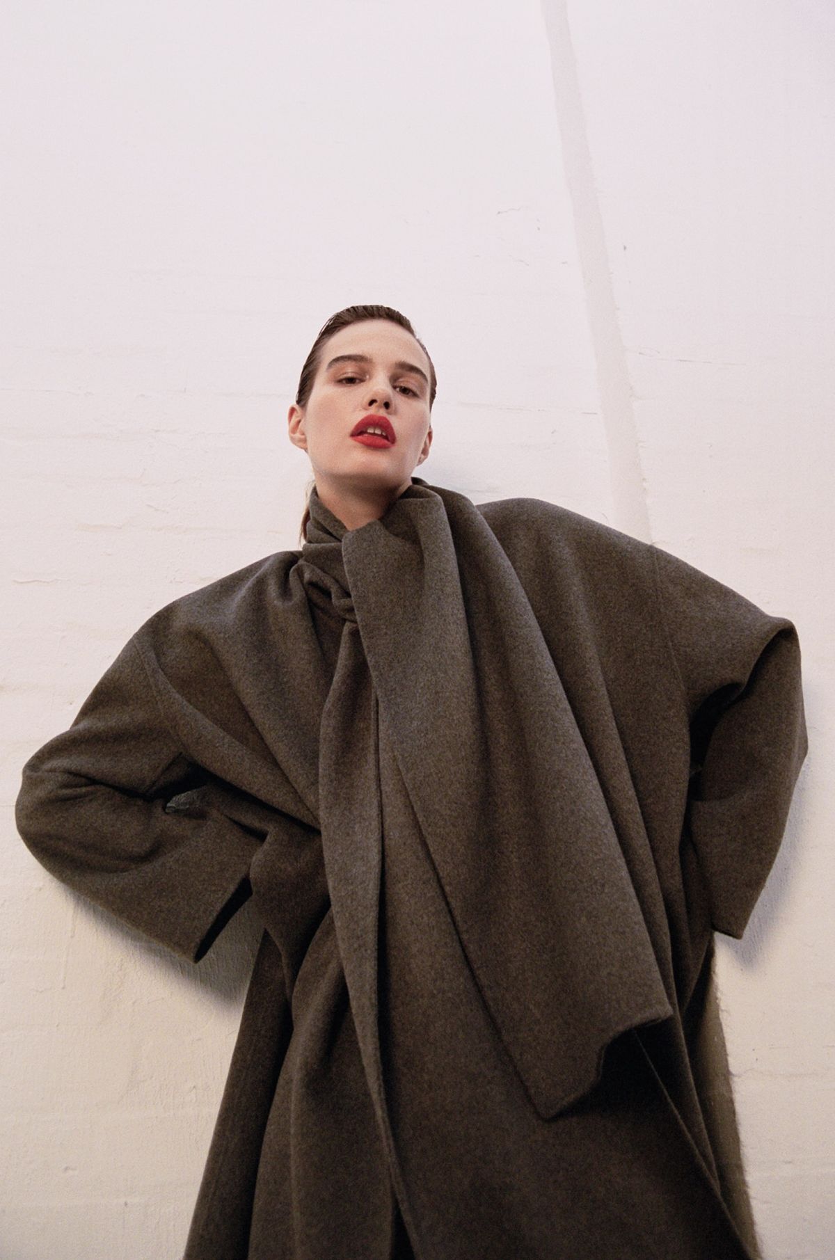 Women wearing grey coat with red lips in white brick studios
