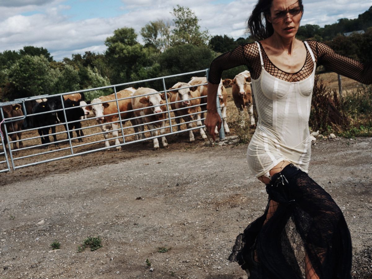 Model running on a farm with cows in the background