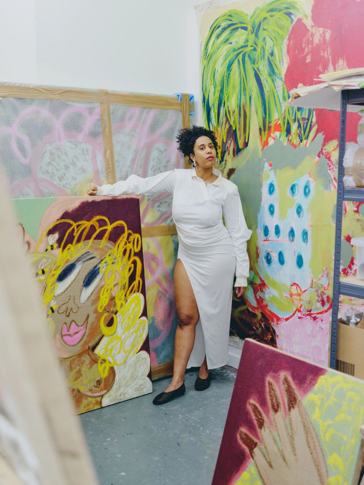 woman standing in her studio amongst her colourful paintings