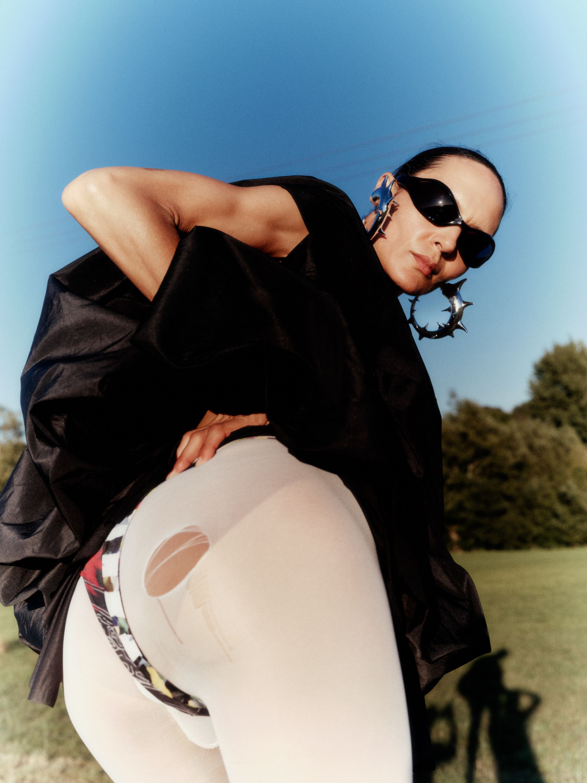 women in filed wearing black lifting up her dress