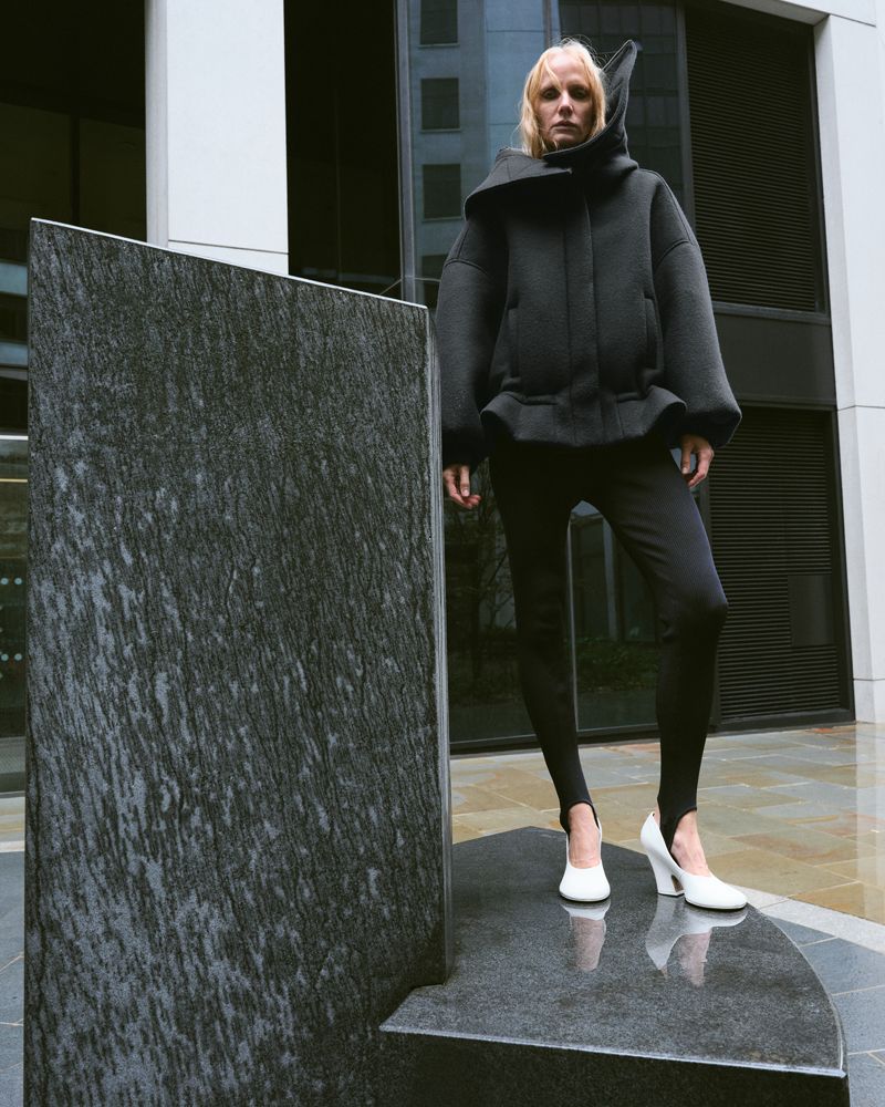 woman standing on concrete sculpture in the city wearing black on a rainy day
