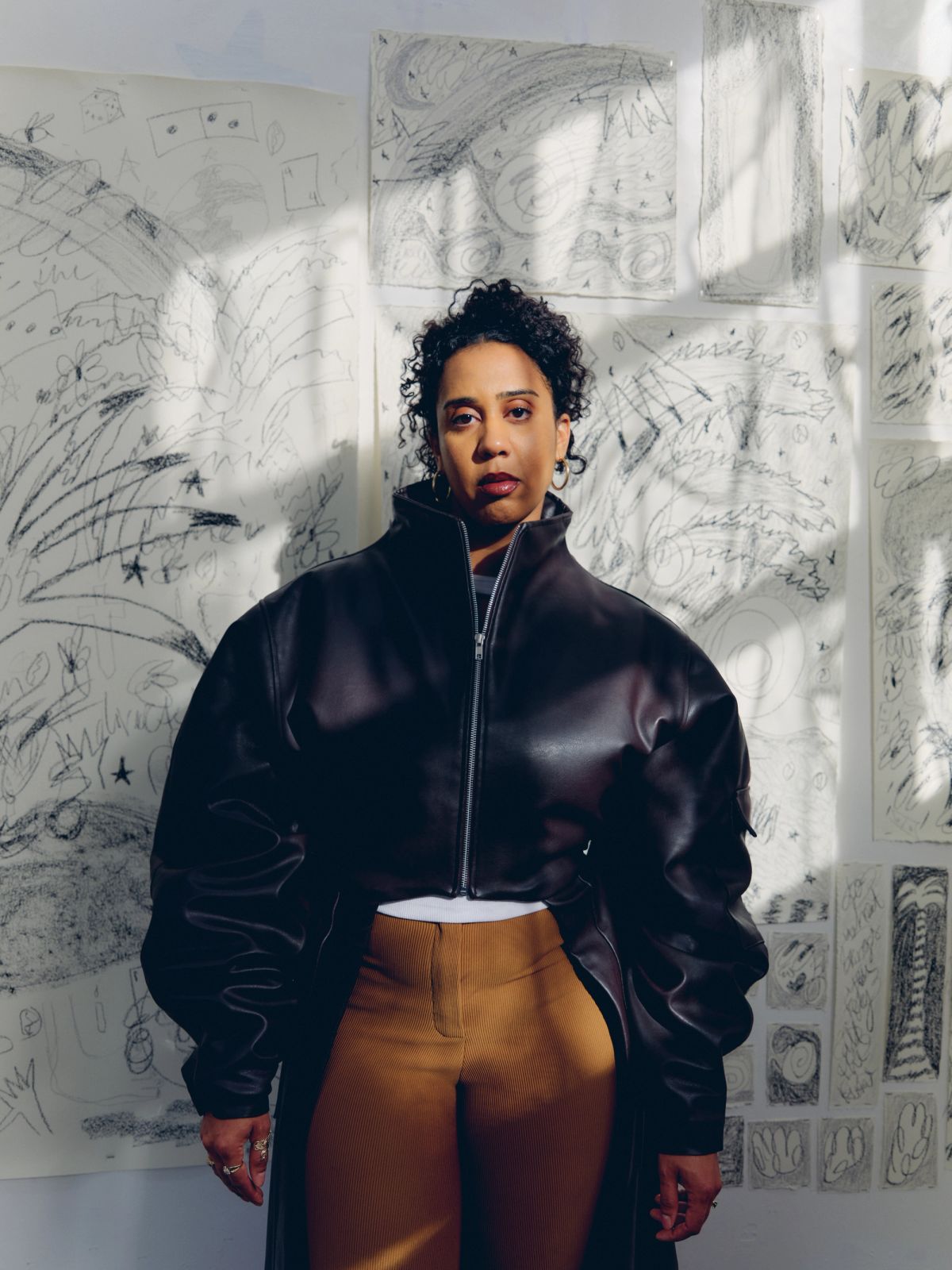 Artist in her studio wearing black jacket and brown trousers