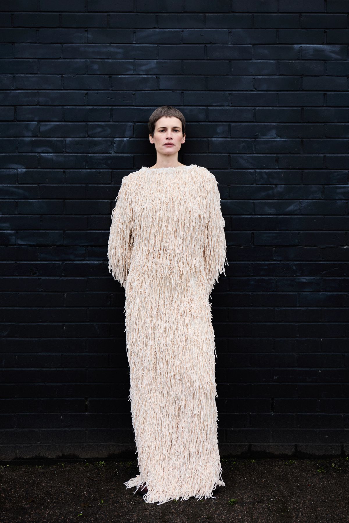 Model wearing textured dress against black wall