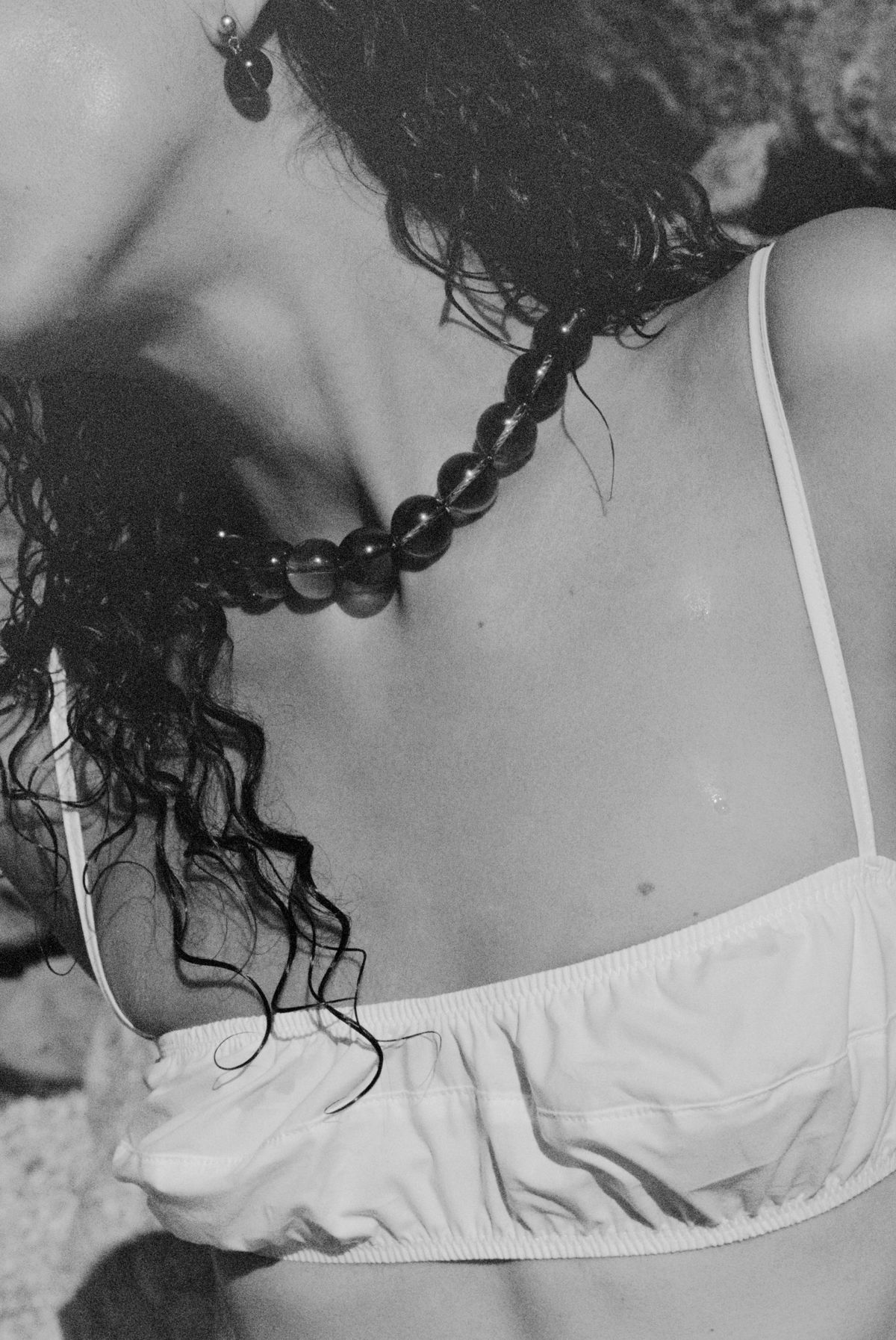 Woman wearing white cotton bra top and bead necklace