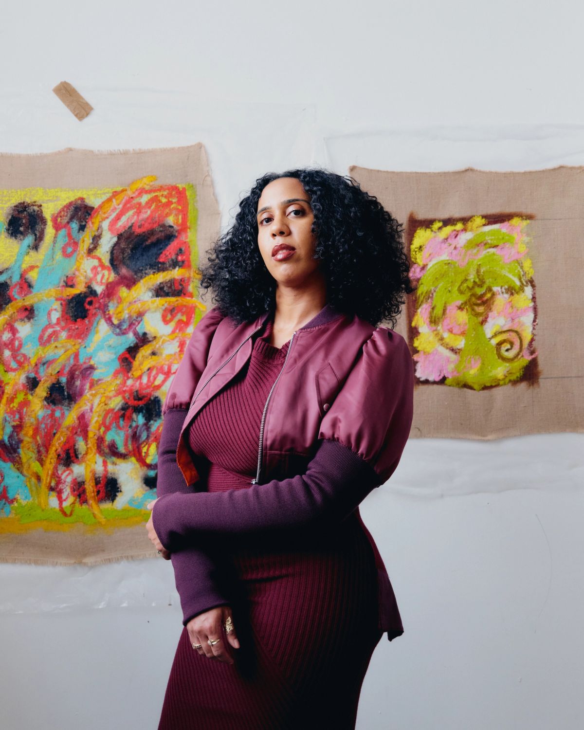 Artist wearing purple standing in front of her paintings