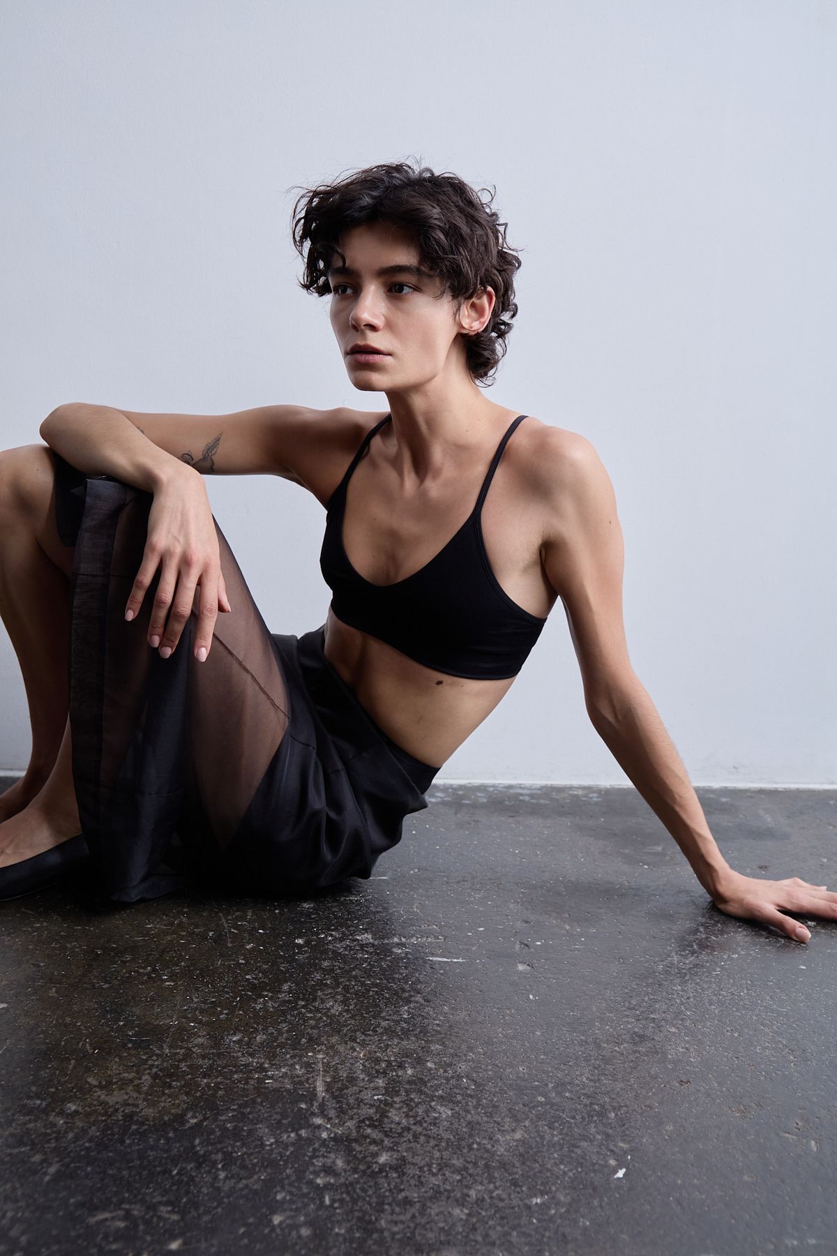 woman sat on floor in black bra and see through skirt