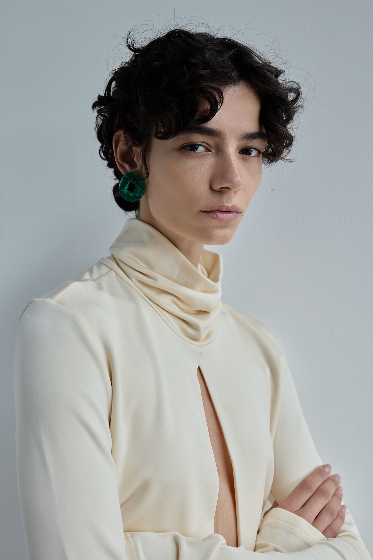 Woman in green earring and cream top