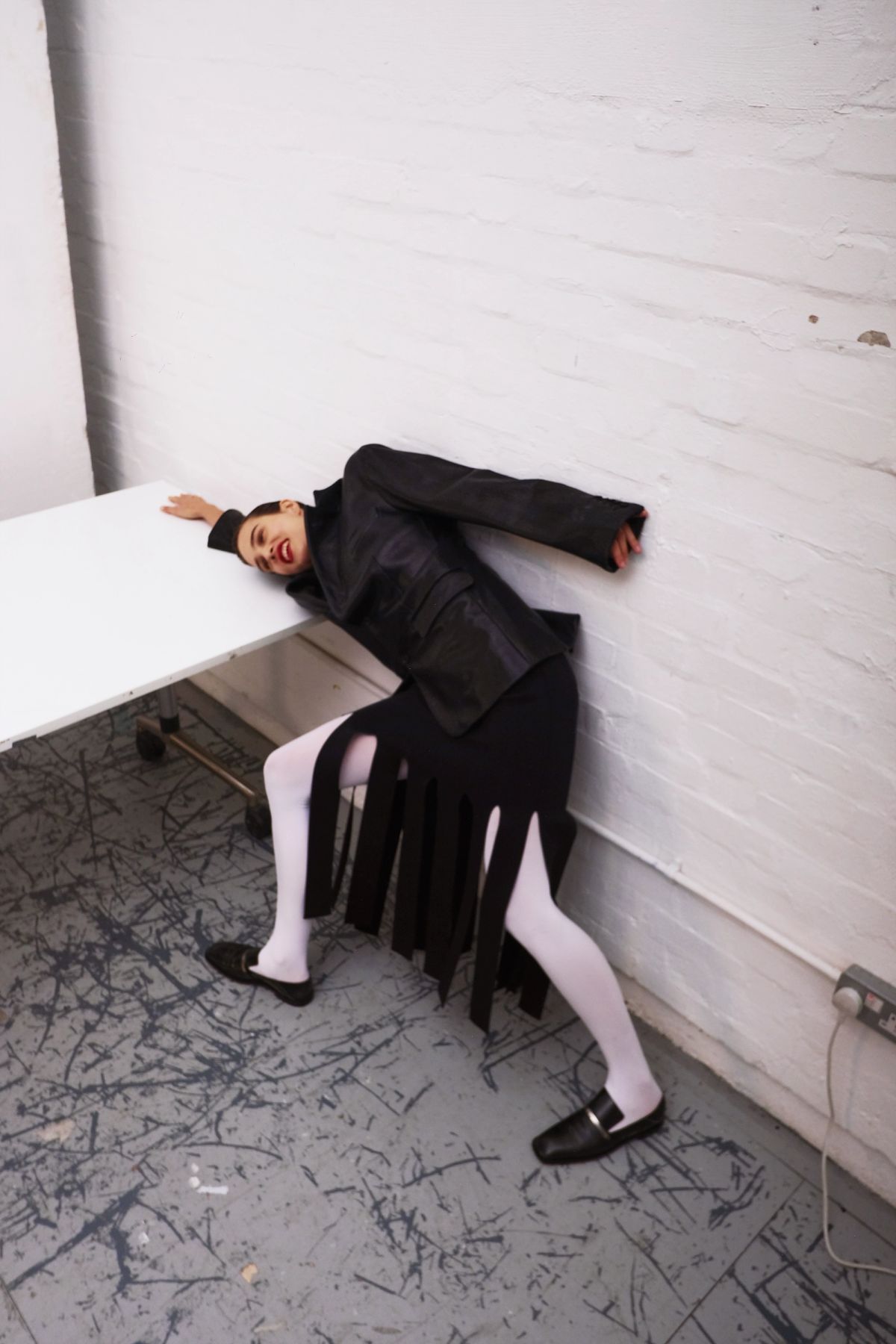 model leaning on a table wearing black