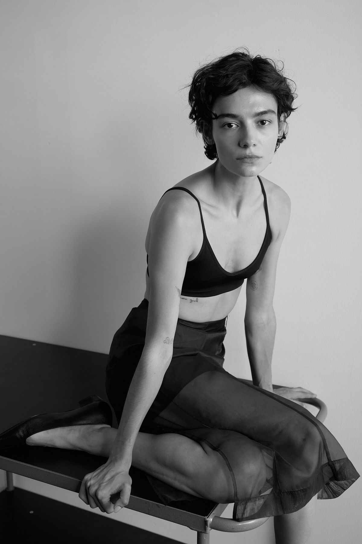 Woman in black bra top and see through skirt sat on table