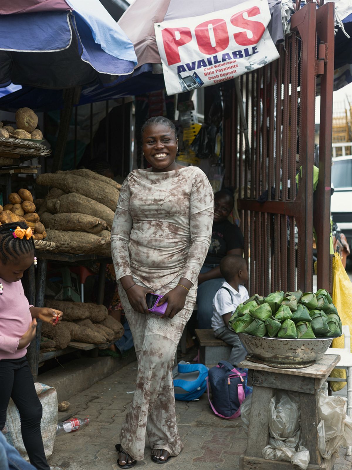 Nigerian woman in a market place smiling with her purple pos machine