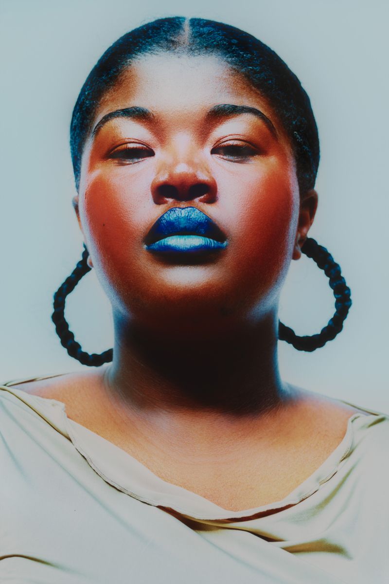 close up of model with braids blue lips on a white background