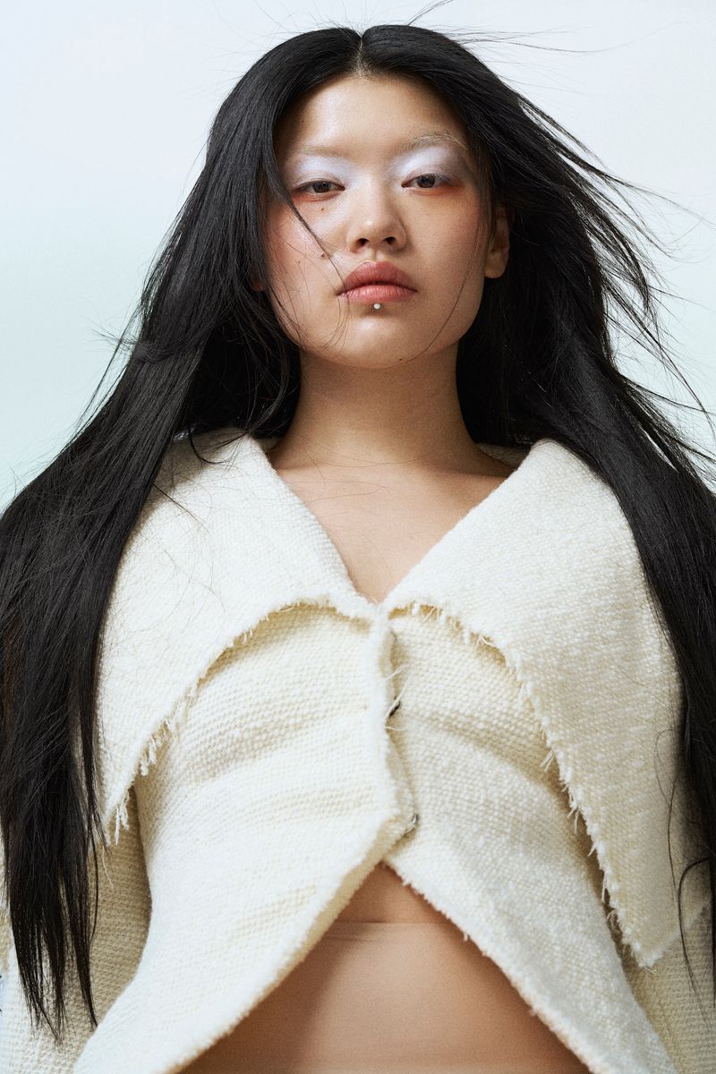 Model wearing a cream jacket with wind in her hair