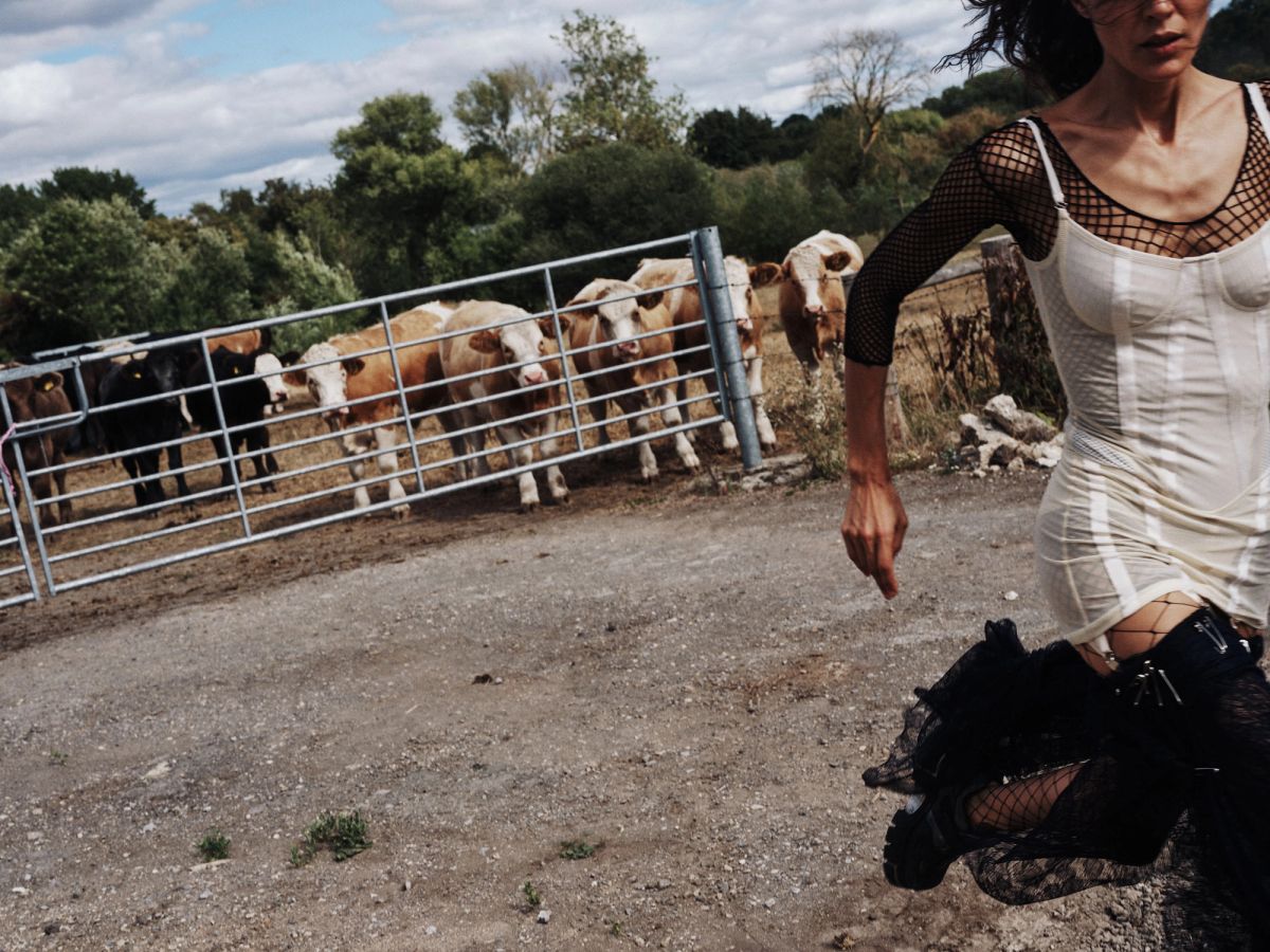 Model running on a farm with cows in the background 2
