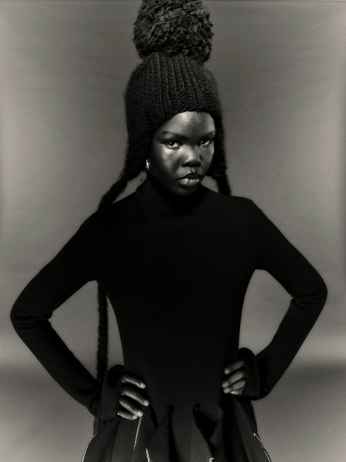 Model wearing a black dress and bobble hat in a studio