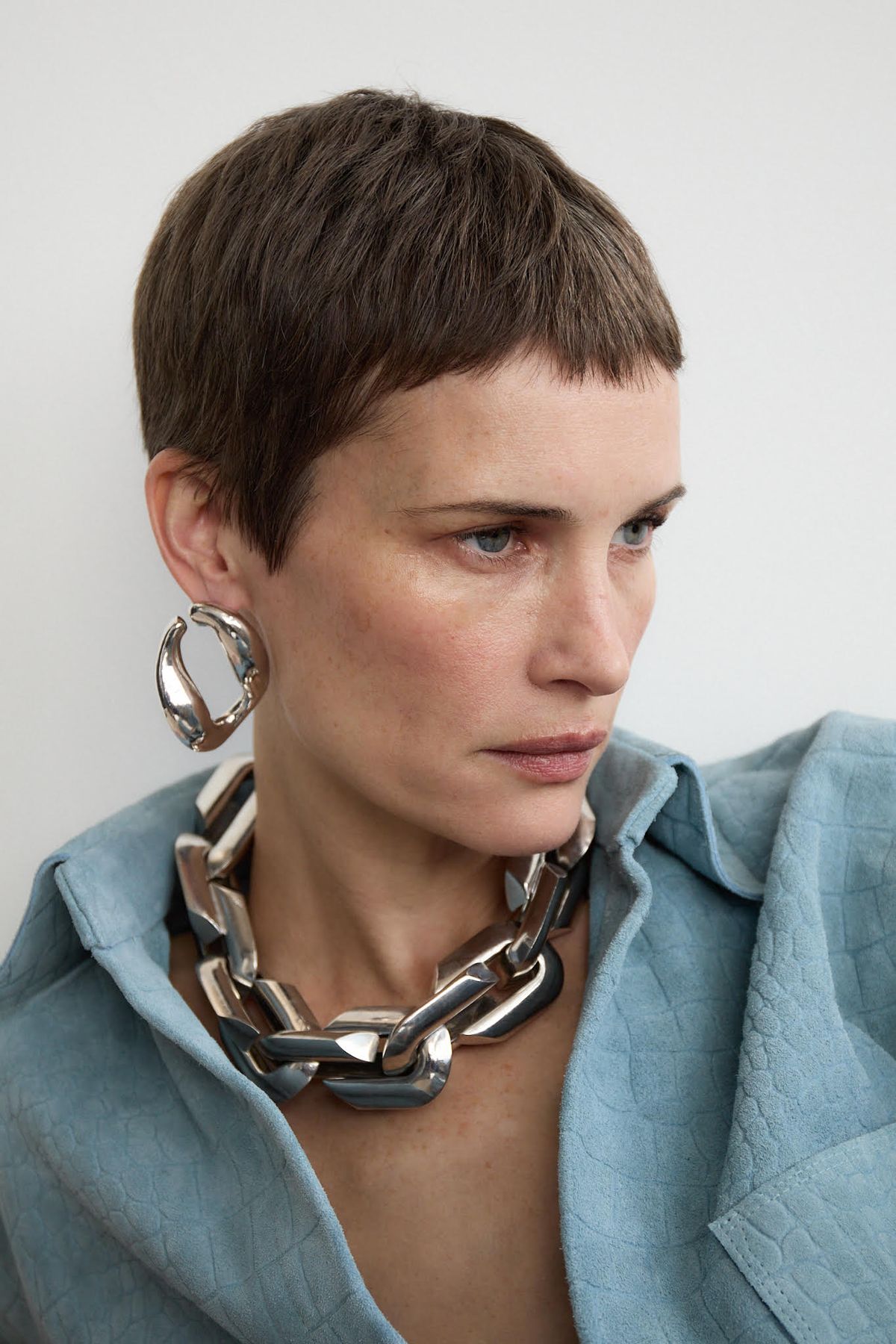 Model wearing chunky silver jewellery and pale blue suede shirt