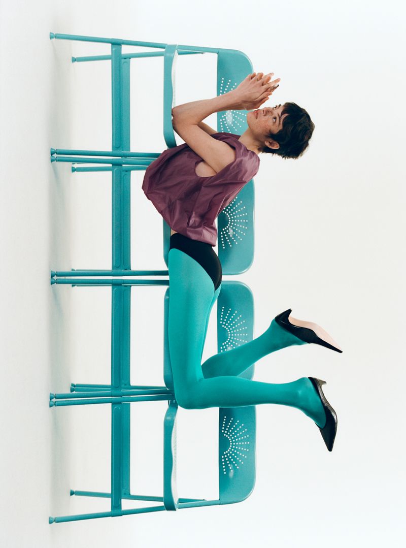 model lying across 4 blue charis on a white background