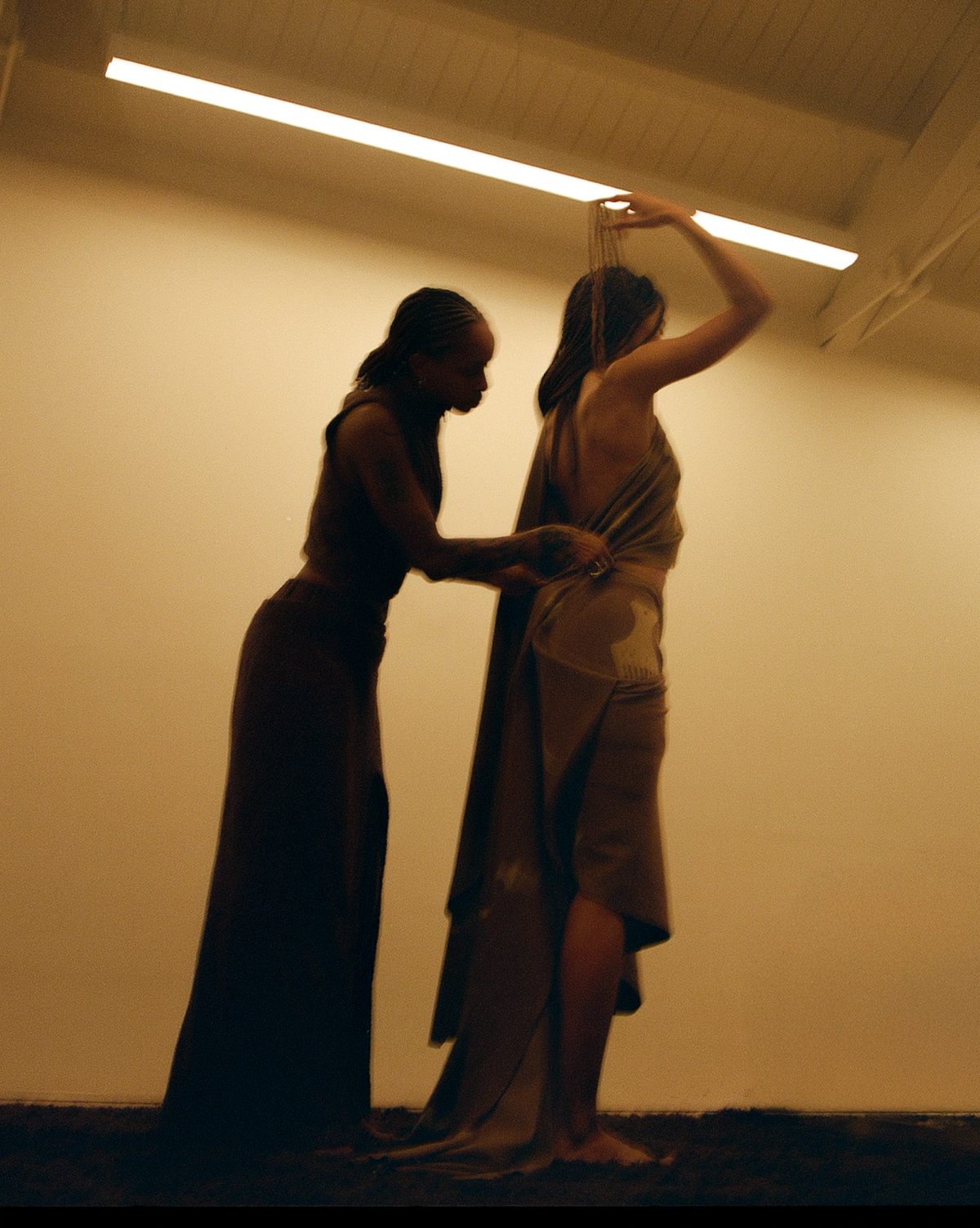 A women drapes fabric around another womens body