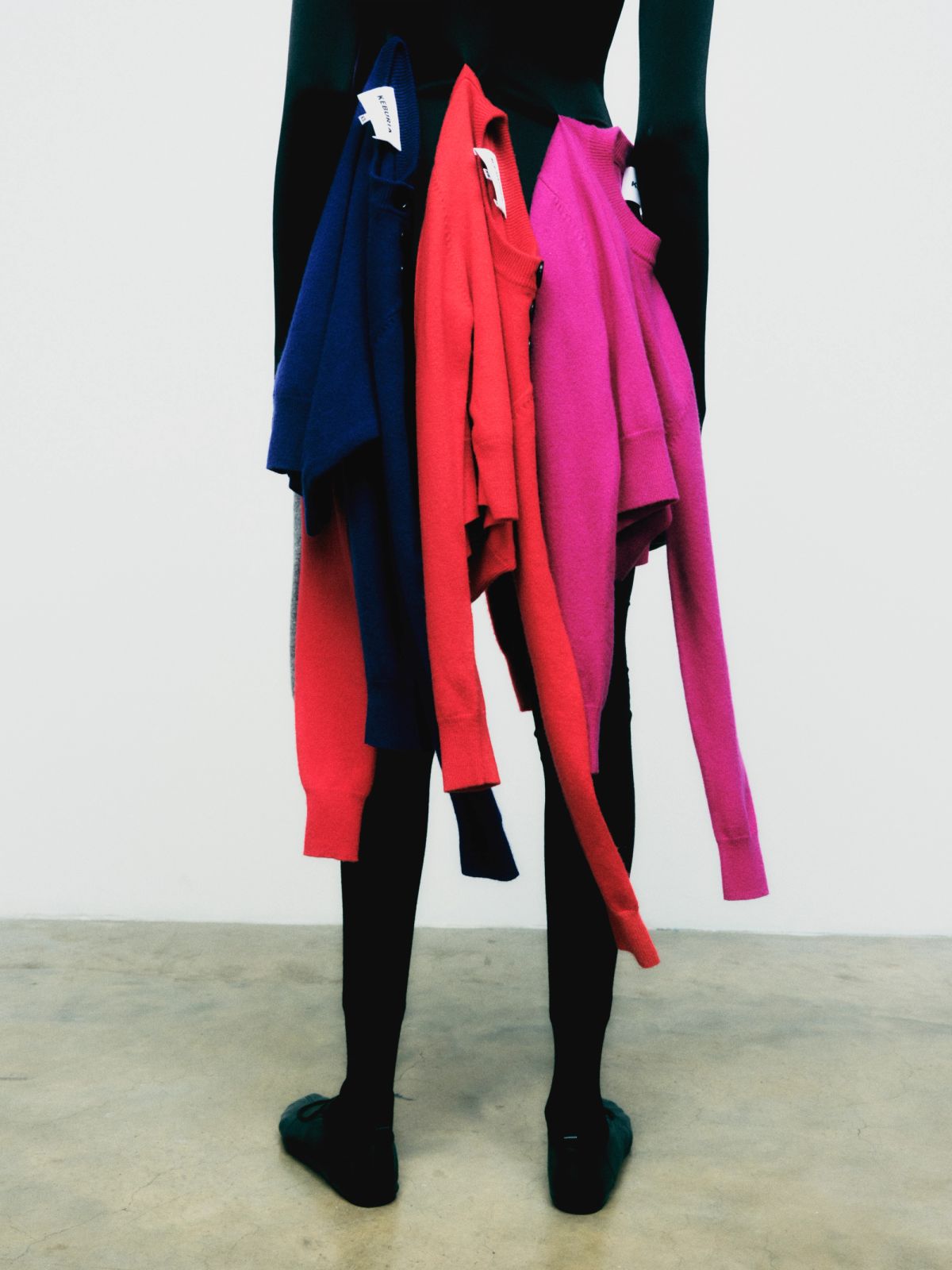 waist down back shot of model with coloured cardigans hanging from them