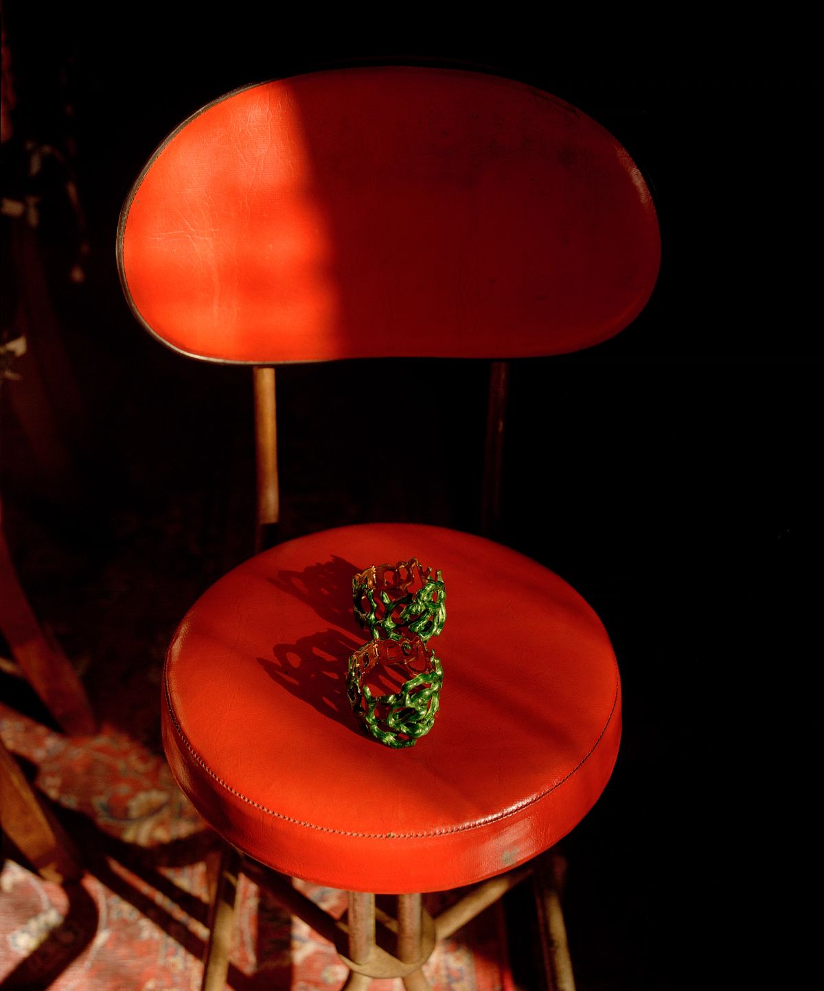 two jade bangles sit on top of a red vinyl chair 
