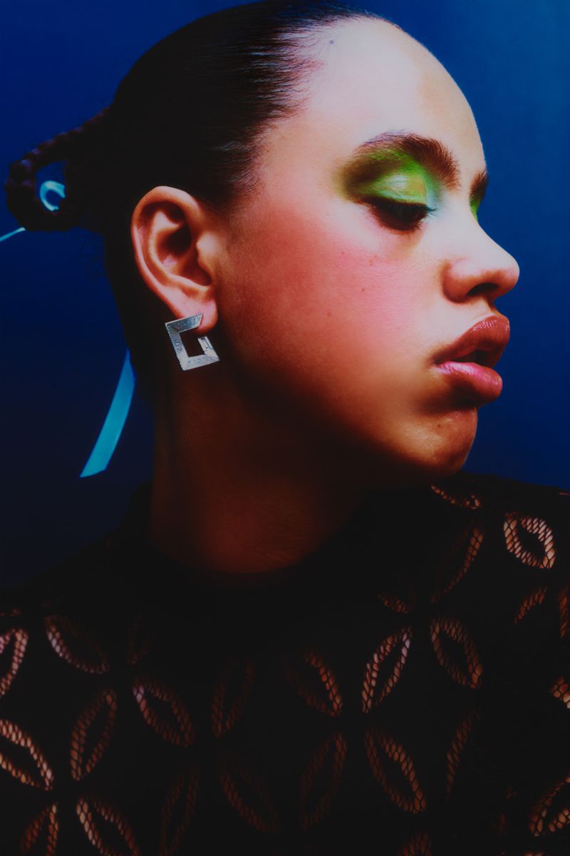 model in profile wearing black dress and green eyeshadow