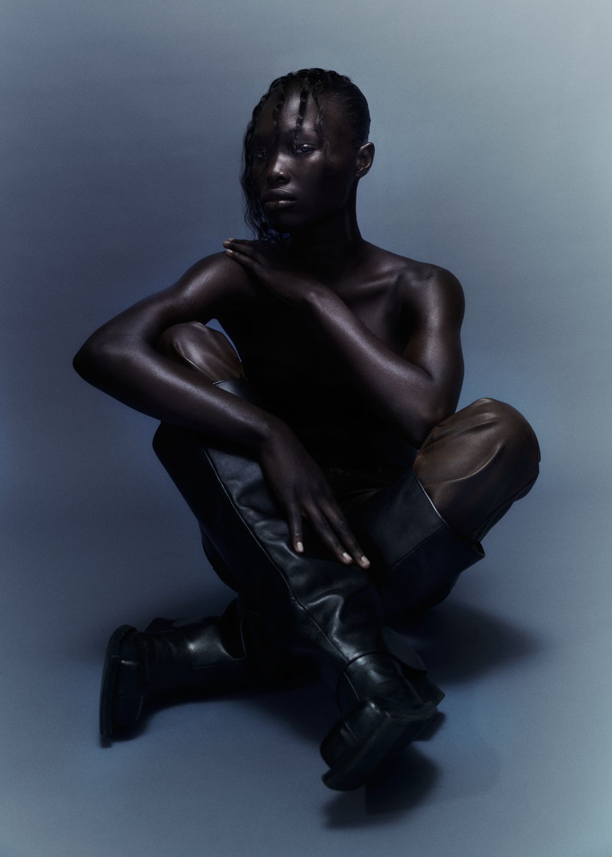 model on dark blue background wearing only black boots